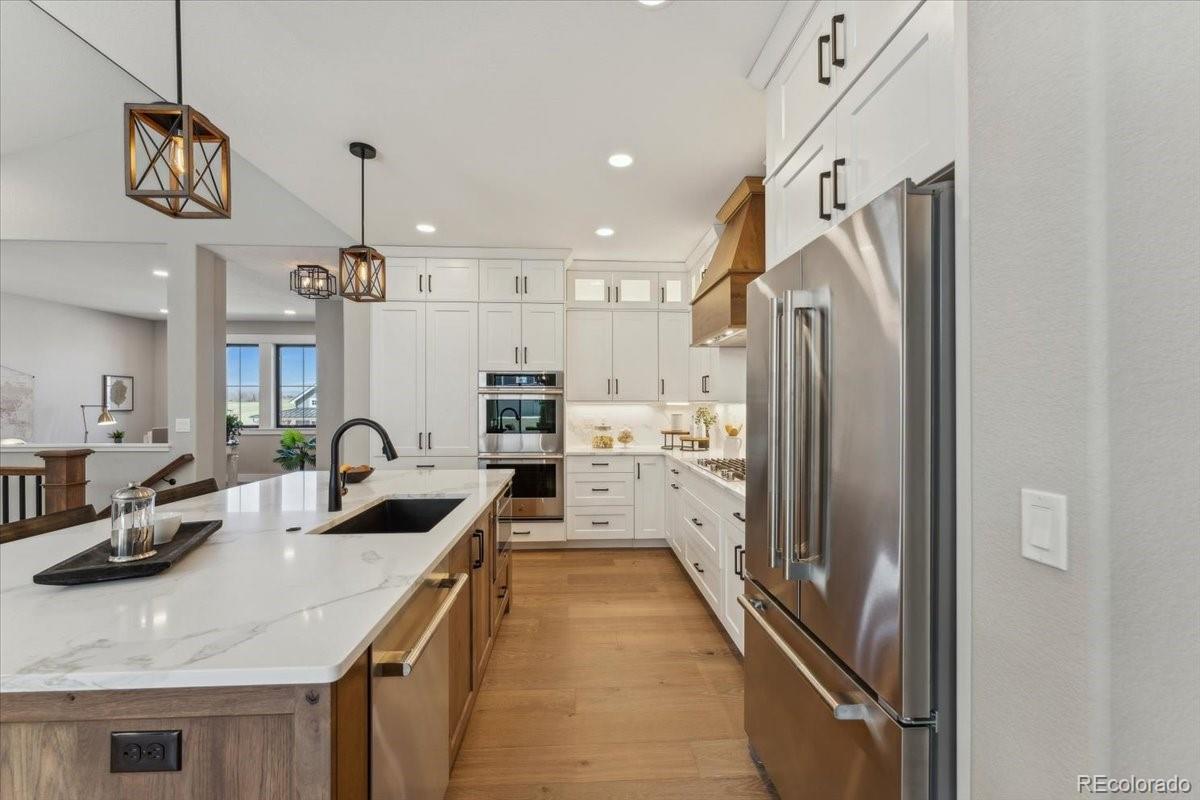 1361 Art Drive Berthoud, CO 80513 - Photo 15 of 40 a kitchen with kitchen island a counter top space a sink a refrigerator and cabinets