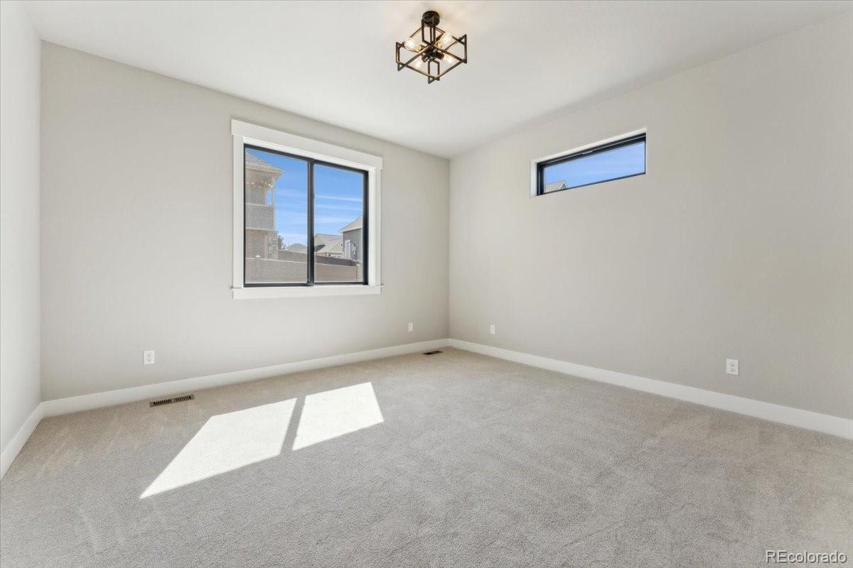 1361 Art Drive Berthoud, CO 80513 - Photo 21 of 40 an empty room with a chandelier fan and windows