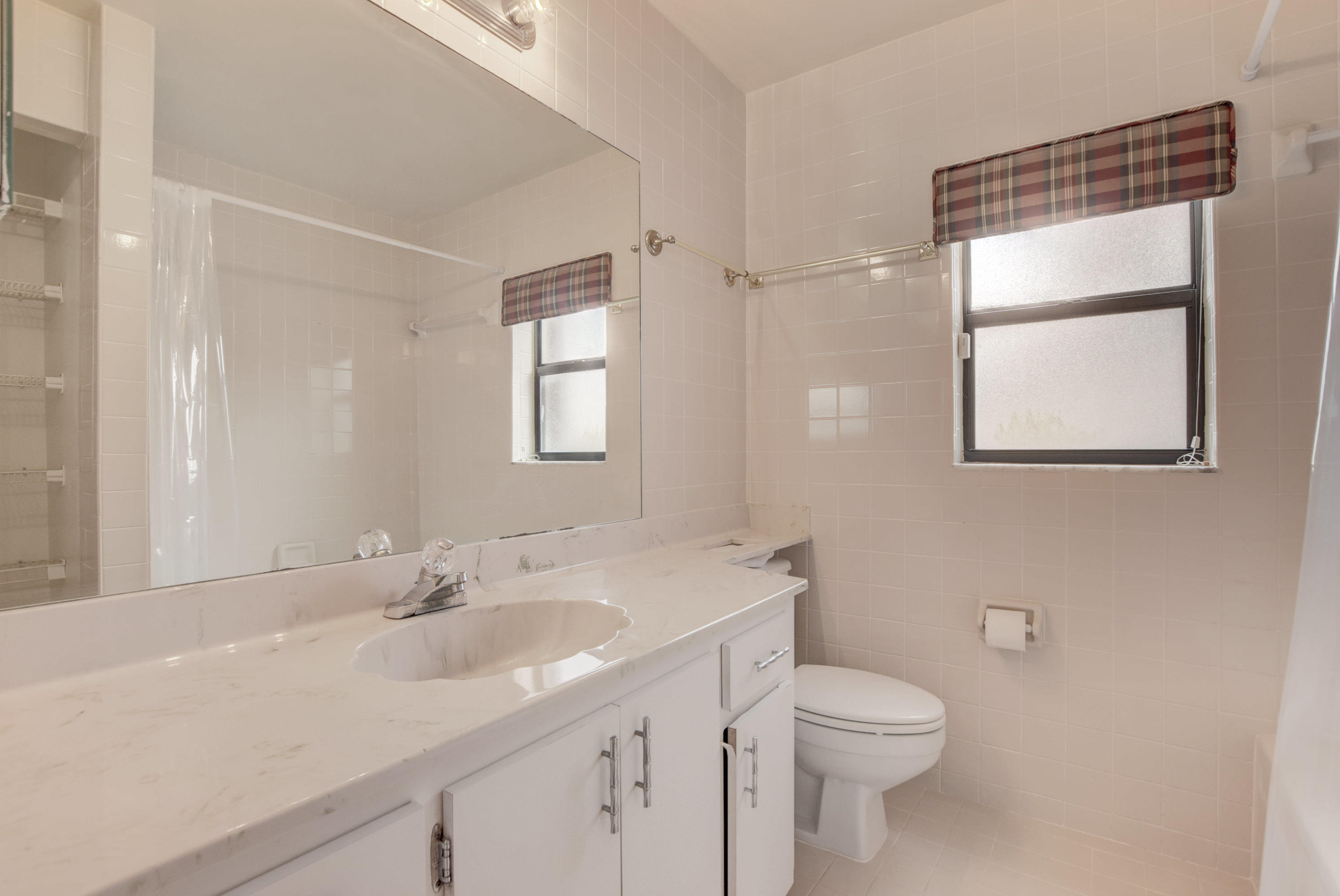 569 Southwest 28th Avenue Delray Beach, FL 33445 - Photo 12 of 25 a bathroom with a toilet a sink a mirror a vanity and window