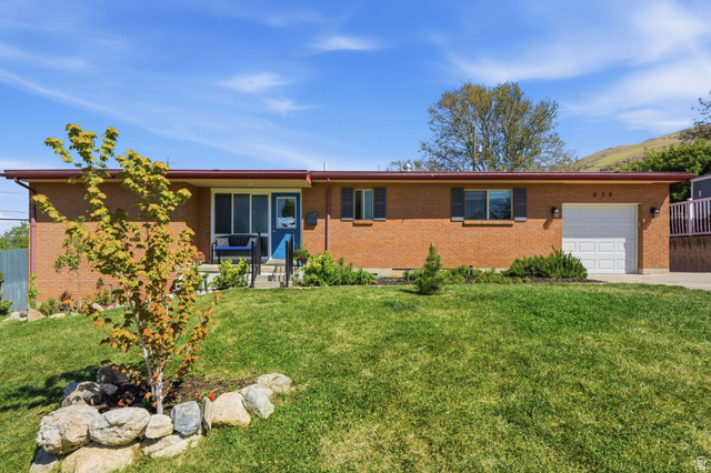 Ranch-style house featuring an attached garage, brick siding, a front lawn, and driveway