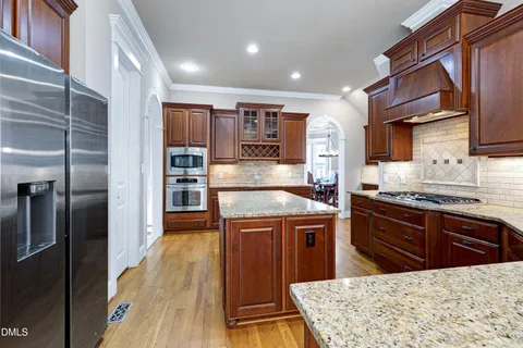 a kitchen with stainless steel appliances granite countertop a stove top oven a sink and a refrigerator