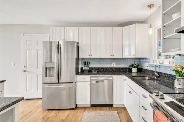 a kitchen with stainless steel appliances granite countertop a stove a sink and white cabinets