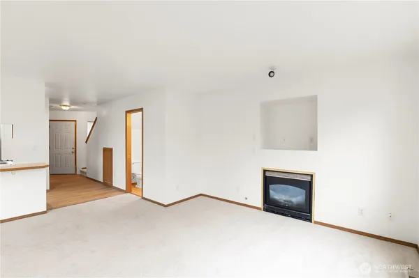 a view of an empty room with wooden floor and a fireplace