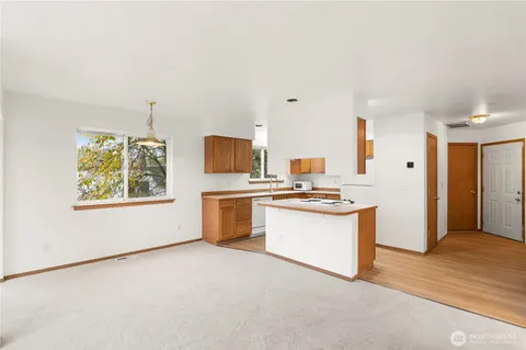 a kitchen with stainless steel appliances a white refrigerator freezer a sink dishwasher and a stove with wooden floor