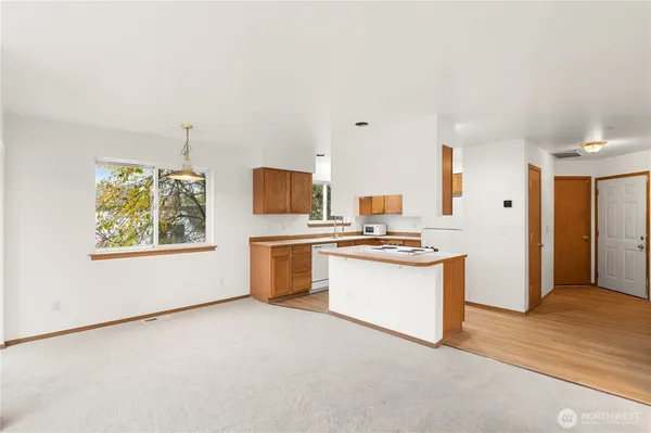 a kitchen with stainless steel appliances a white refrigerator freezer a sink dishwasher and a stove with wooden floor