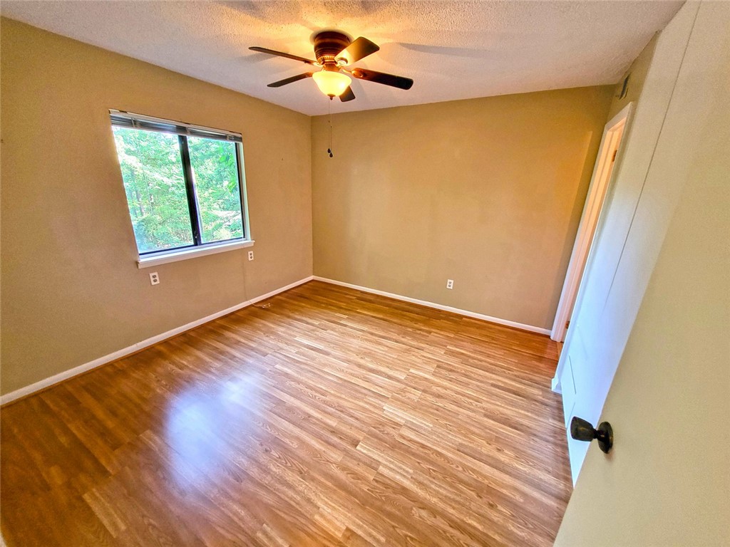 150 Ligon Street, Unit 1001 Clemson, SC 29631 - Photo 13 of 29 Wood flooring and a window overlooking nature create a calm atmosphere in this bedroom.