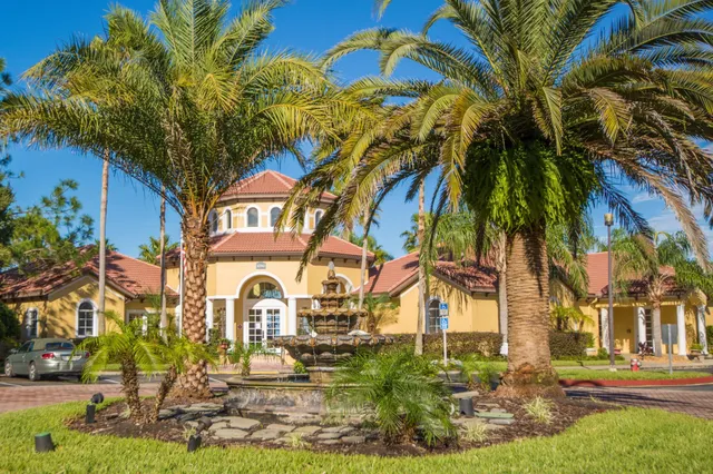 a view of a swimming pool with a yard and palm trees