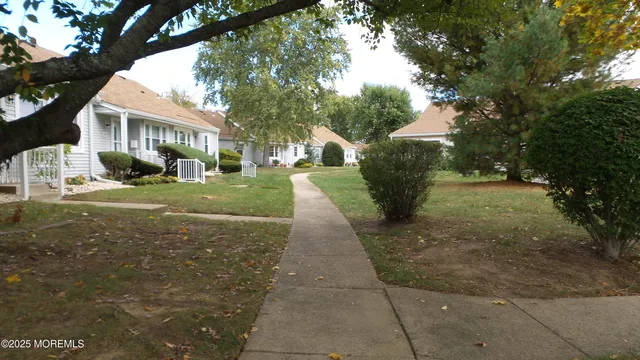 a view of a yard in front of a brick house with large windows