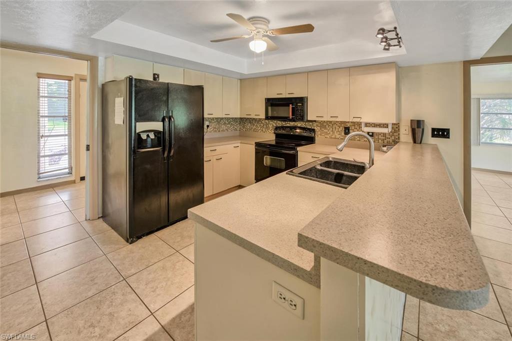 29 Caribbean Road Naples, FL 34108 - Photo 9 of 30 a kitchen with stainless steel appliances a refrigerator a stove a sink a dining table and chairs