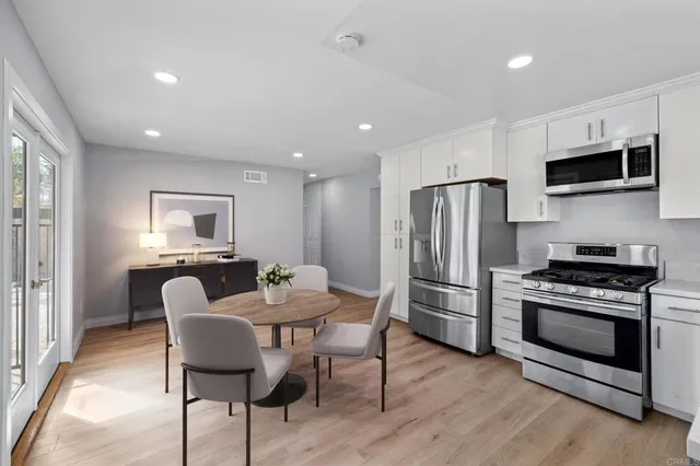 a kitchen with stainless steel appliances a stove a sink a refrigerator a dining table and chairs