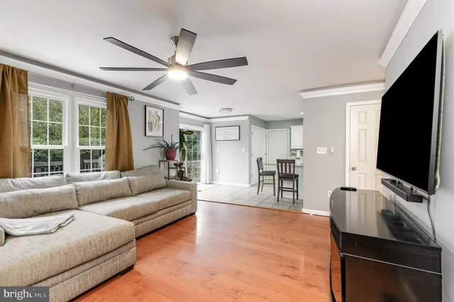 a living room with furniture a ceiling fan and a flat screen tv