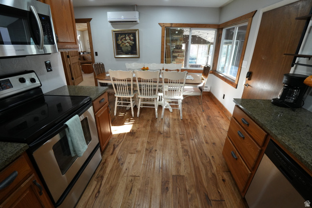 3711 North Canyon Road Provo, UT 84604 - Photo 6 of 42 Kitchen with stainless steel appliances, brown cabinetry, dark wood-type flooring, dark stone countertops, and a wall mounted AC