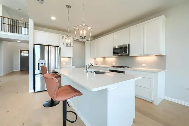 a kitchen with stainless steel appliances granite countertop a sink refrigerator stove and microwave