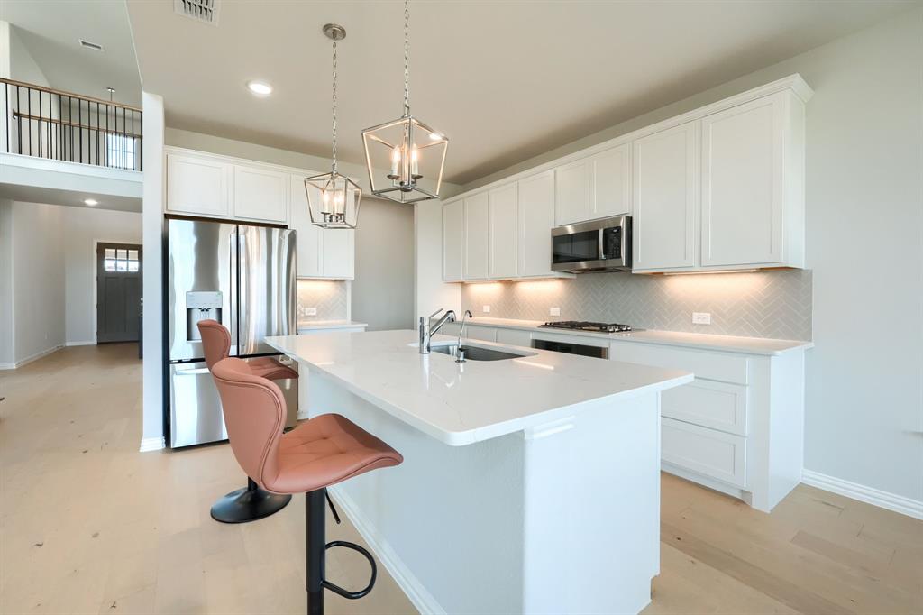 1309 Buttercup Road Prosper, TX 75078 - Photo 16 of 36 a kitchen with stainless steel appliances granite countertop a sink refrigerator stove and microwave