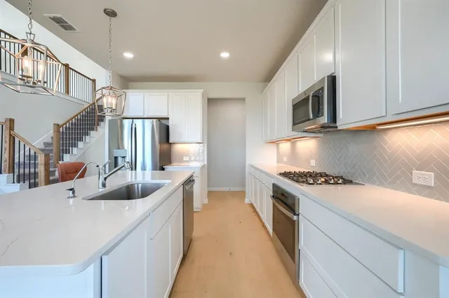 a kitchen with granite countertop a sink stainless steel appliances and cabinets