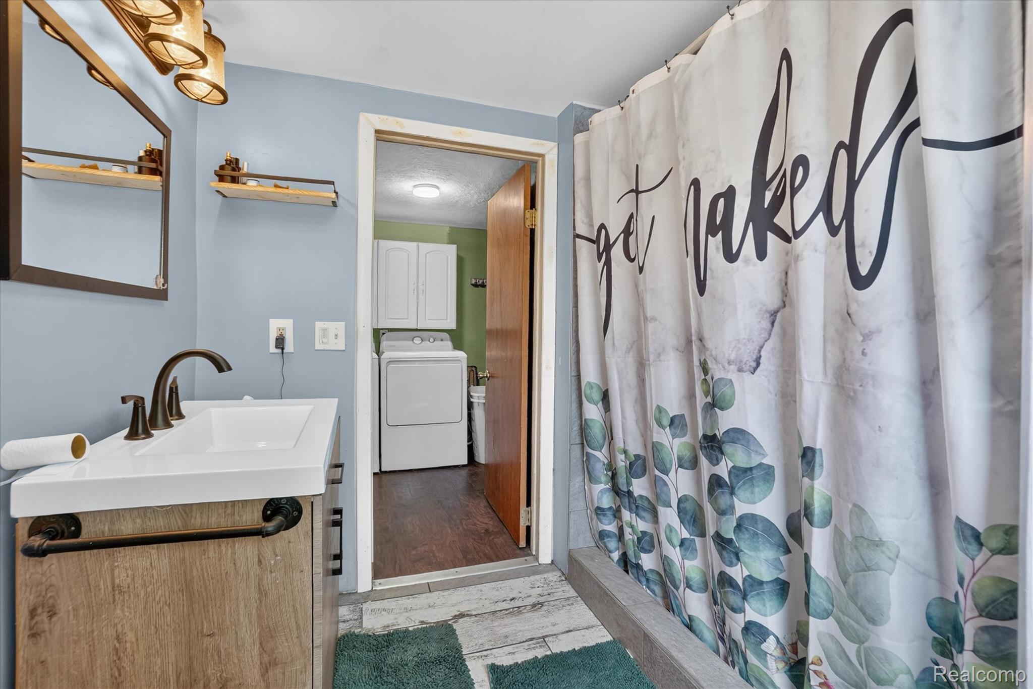 508 Deland Road Flushing, MI 48433 - Photo 21 of 38 Bathroom featuring a floating wood-finish vanity with a white countertop and bronze-finish faucet, a bronze-framed mirror, and a wall-mounted light fixture