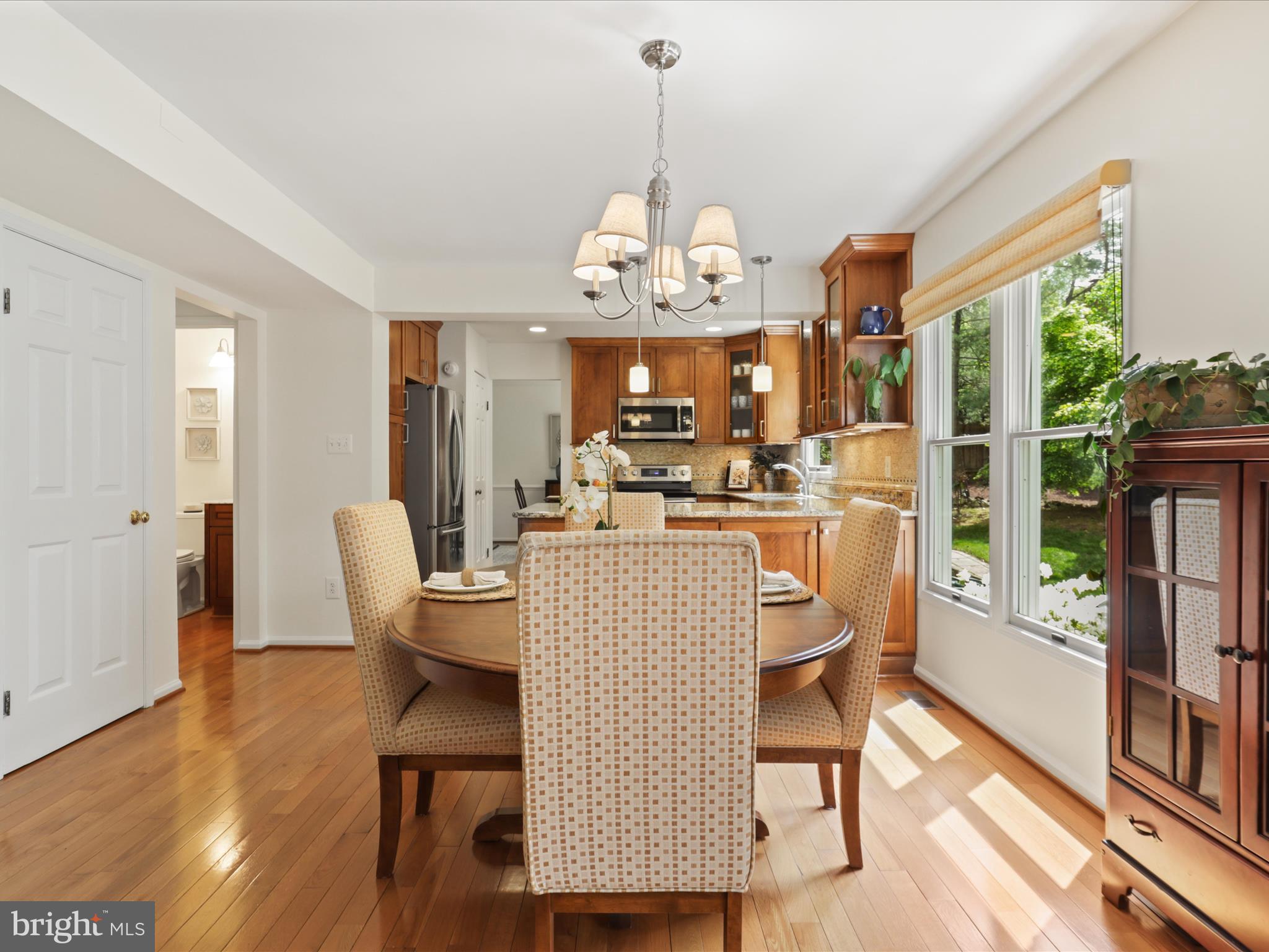 12021 Heather Down Drive Herndon, VA 20170 - Photo 12 of 47 a dining room with wooden floor a chandelier a glass table and chairs