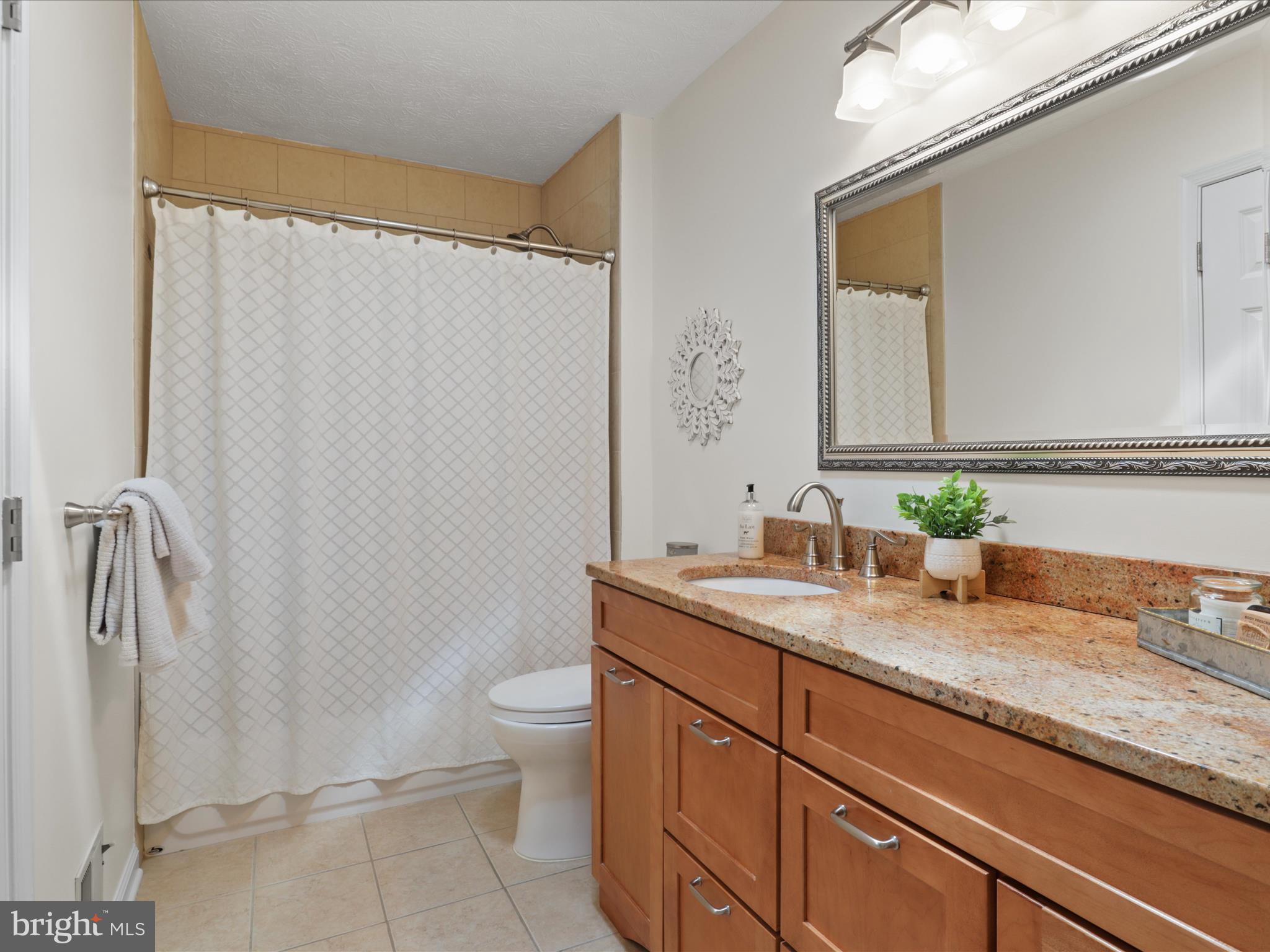 12021 Heather Down Drive Herndon, VA 20170 - Photo 30 of 47 a bathroom with a granite countertop sink a toilet and a mirror