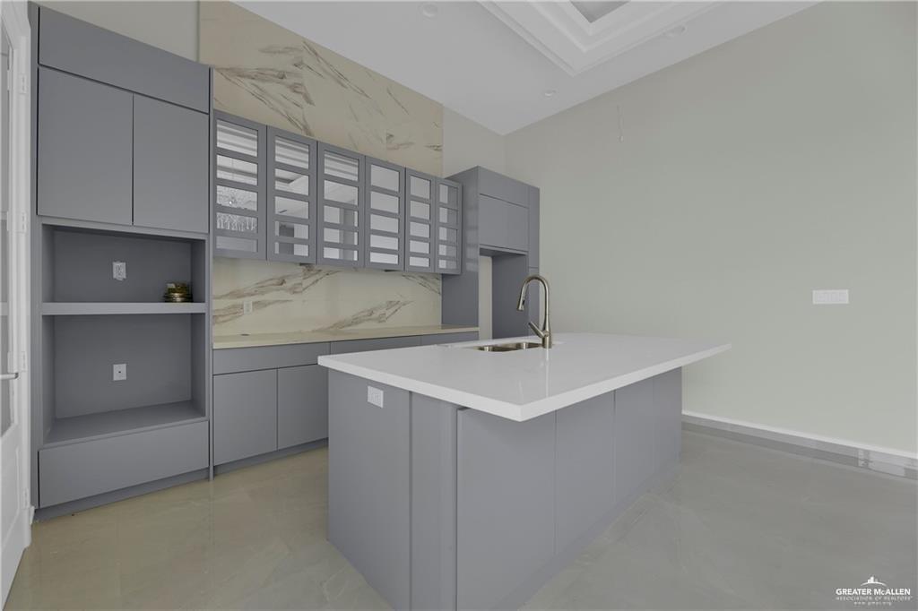 2516 Viola Street Mission, TX 78574 - Photo 8 of 17 Kitchen featuring gray cabinets, a kitchen island with sink, modern cabinets, and tasteful backsplash