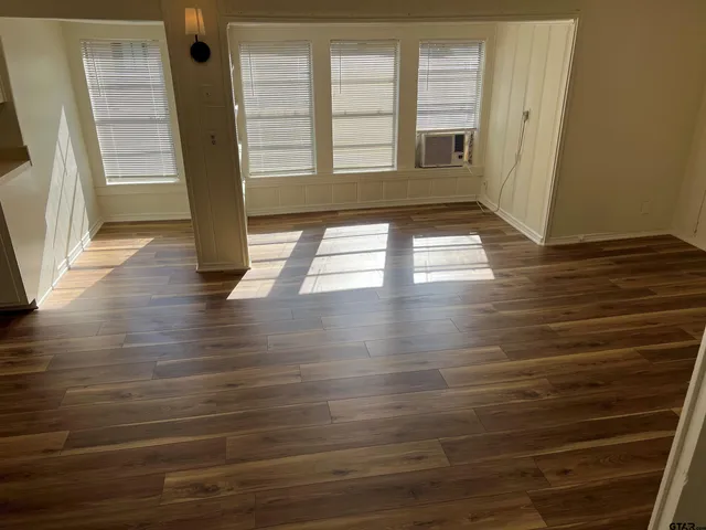 a view of empty room with wooden floor and fan