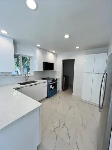 a large white kitchen with a sink stainless steel appliances and cabinets