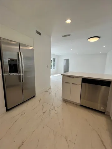 a kitchen with stainless steel appliances granite countertop a refrigerator a sink and a stove