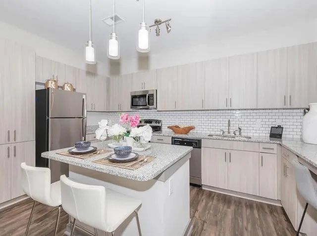 a kitchen with kitchen island granite countertop a sink cabinets and stainless steel appliances