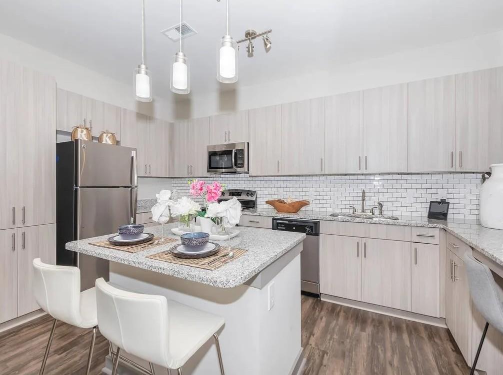 a kitchen with kitchen island granite countertop a sink cabinets and stainless steel appliances