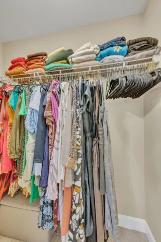 a view of walk in closet with clothes and shoes