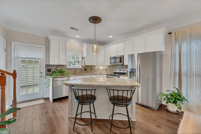 a kitchen with stainless steel appliances granite countertop a table chairs refrigerator and a sink