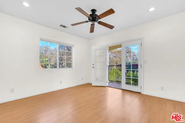 an empty room with windows and ceiling fan