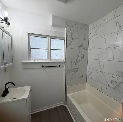 a white bath tub sitting next to a white sink and vanity