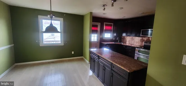 a kitchen with stainless steel appliances granite countertop a stove and a wooden floors