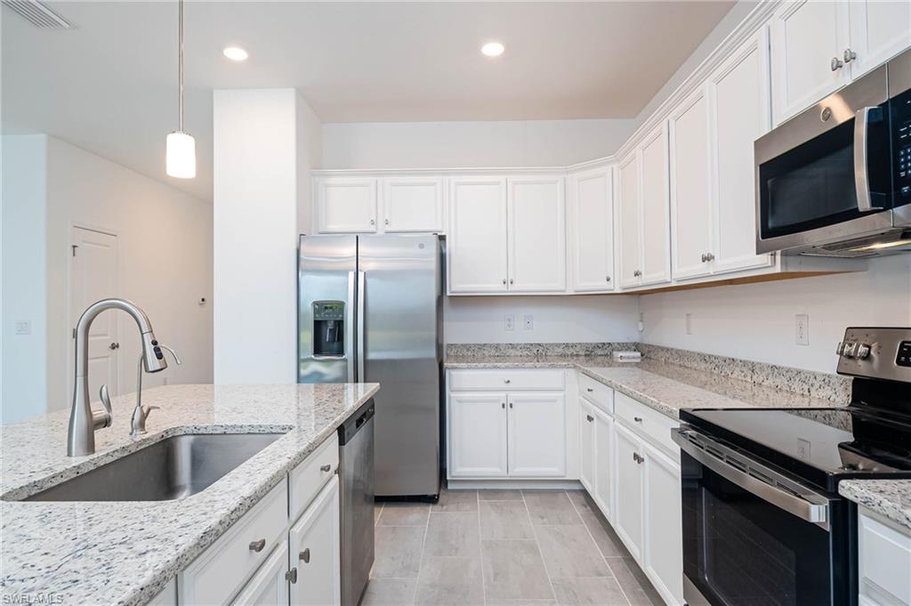 2418 Orchard Street Naples, FL 34120 - Photo 11 of 35 Kitchen with light stone counters, stainless steel appliances, sink, pendant lighting, and white cabinets