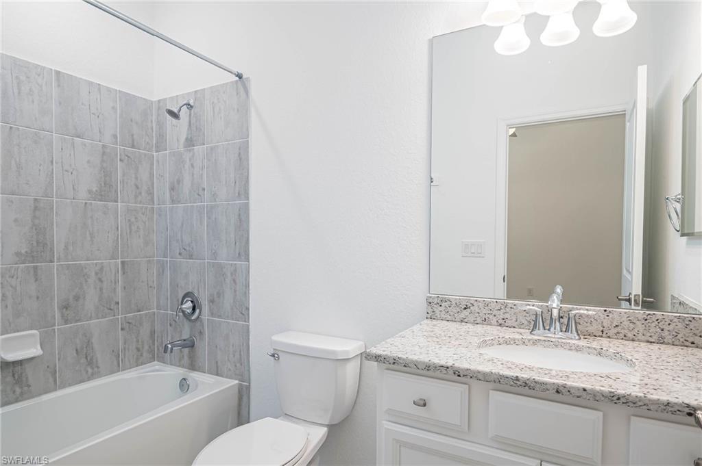 2418 Orchard Street Naples, FL 34120 - Photo 21 of 35 Full bathroom featuring vanity, tiled shower / bath combo, and toilet