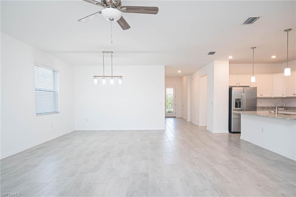 2418 Orchard Street Naples, FL 34120 - Photo 5 of 35 Unfurnished living room featuring ceiling fan, sink, a healthy amount of sunlight, and light hardwood / wood-style flooring