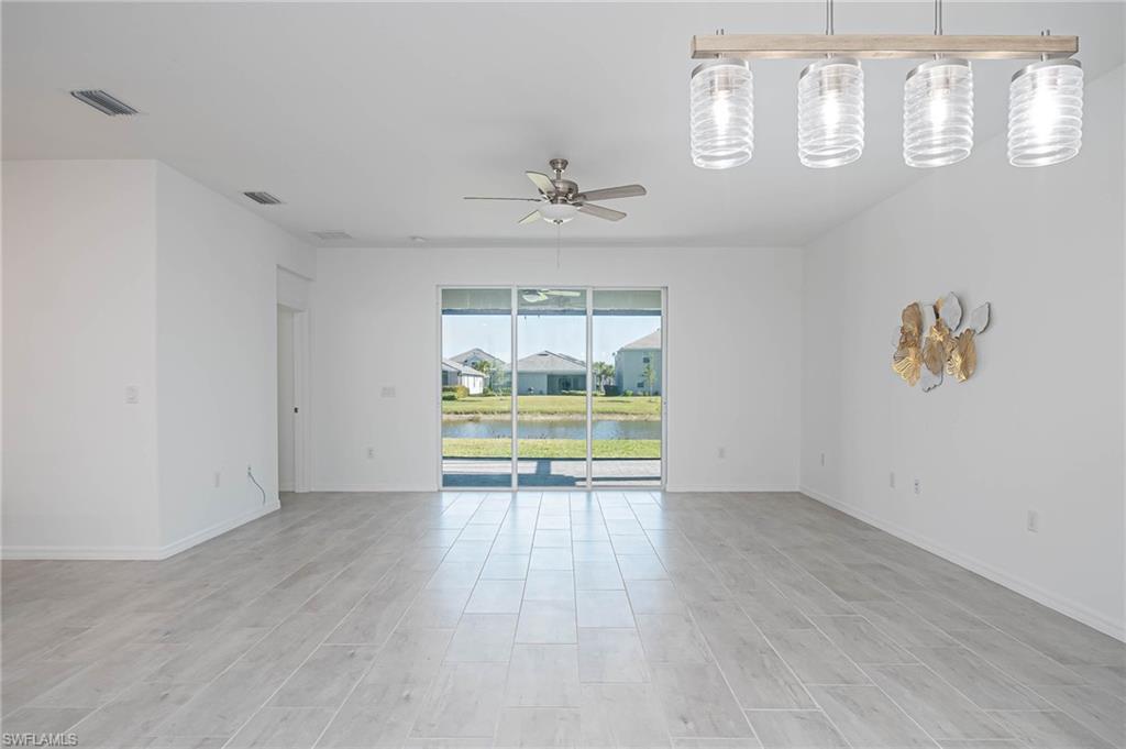 2418 Orchard Street Naples, FL 34120 - Photo 6 of 35 Empty room with ceiling fan, light hardwood / wood-style floors, and a water view