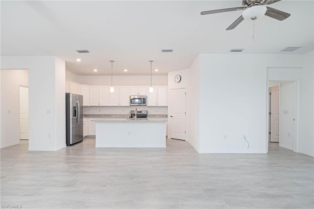 2418 Orchard Street Naples, FL 34120 - Photo 8 of 35 Kitchen featuring pendant lighting, a kitchen island with sink, white cabinets, ceiling fan, and stainless steel appliances