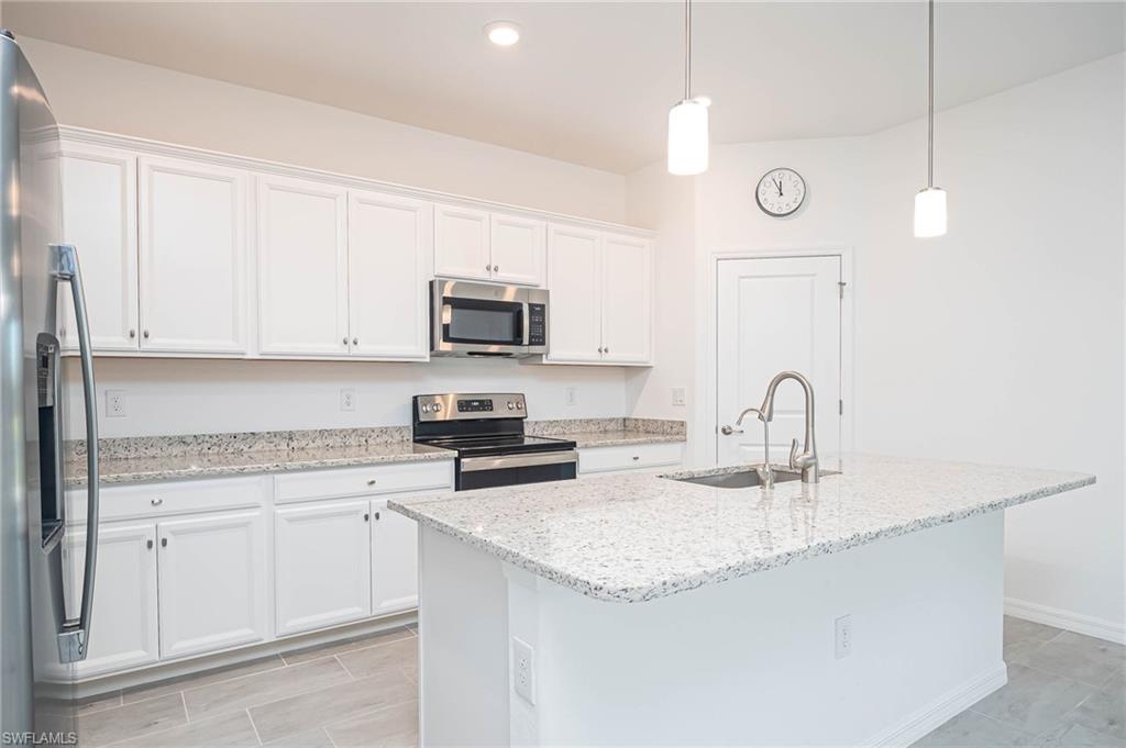 2418 Orchard Street Naples, FL 34120 - Photo 9 of 35 Kitchen with appliances with stainless steel finishes, white cabinetry, a kitchen island with sink, and pendant lighting