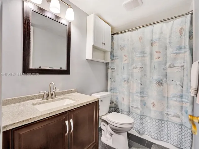 a bathroom with a granite countertop sink toilet and shower