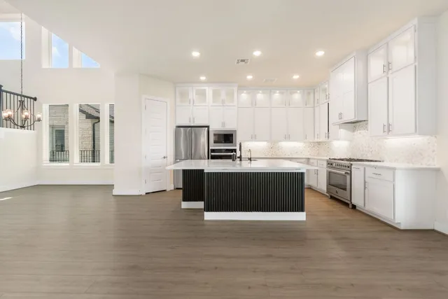a kitchen with stainless steel appliances kitchen island granite countertop a stove a sink and a refrigerator