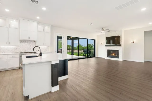 a large kitchen with stainless steel appliances a large counter top a stove a sink and a refrigerator