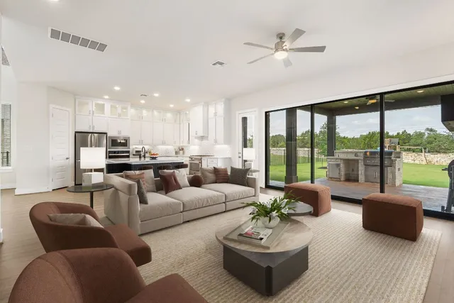 a living room with furniture and a large window with kitchen view