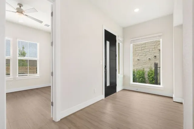 an empty room with wooden floor cabinet and windows