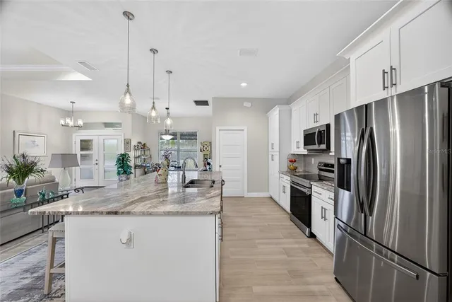 a kitchen with stainless steel appliances granite countertop a refrigerator a stove a sink and a center island