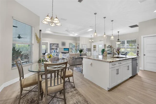 a kitchen with stainless steel appliances kitchen island granite countertop a table chairs and a chandelier