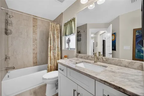 a bathroom with a granite countertop sink a toilet a mirror a bathtub and shower