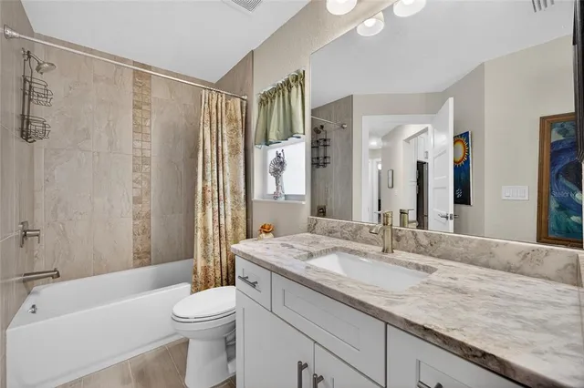 a bathroom with a granite countertop sink a toilet a mirror a bathtub and shower