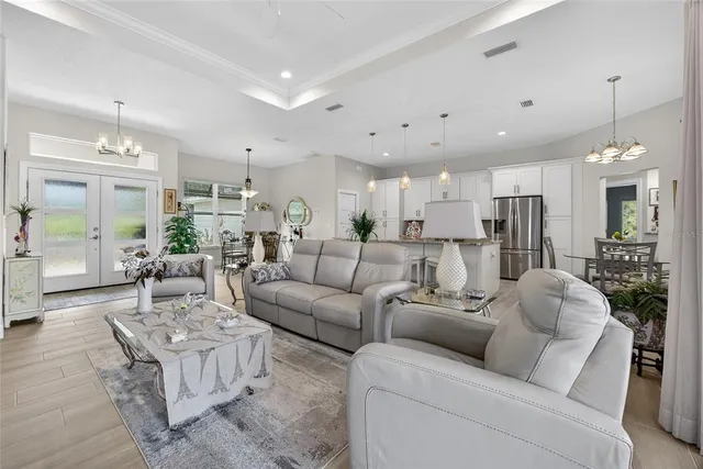 a living room with furniture kitchen view and a chandelier