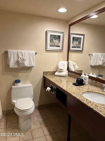 a bathroom with a granite countertop toilet sink and mirror